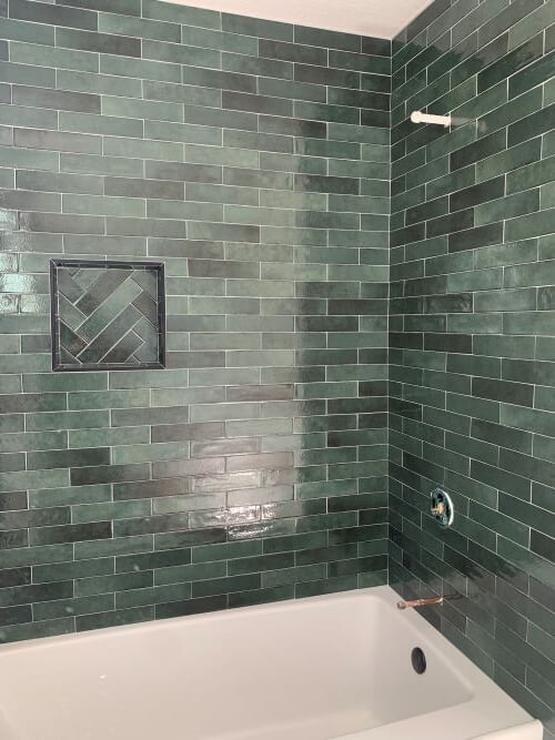 Bathtub surround with green tiles.